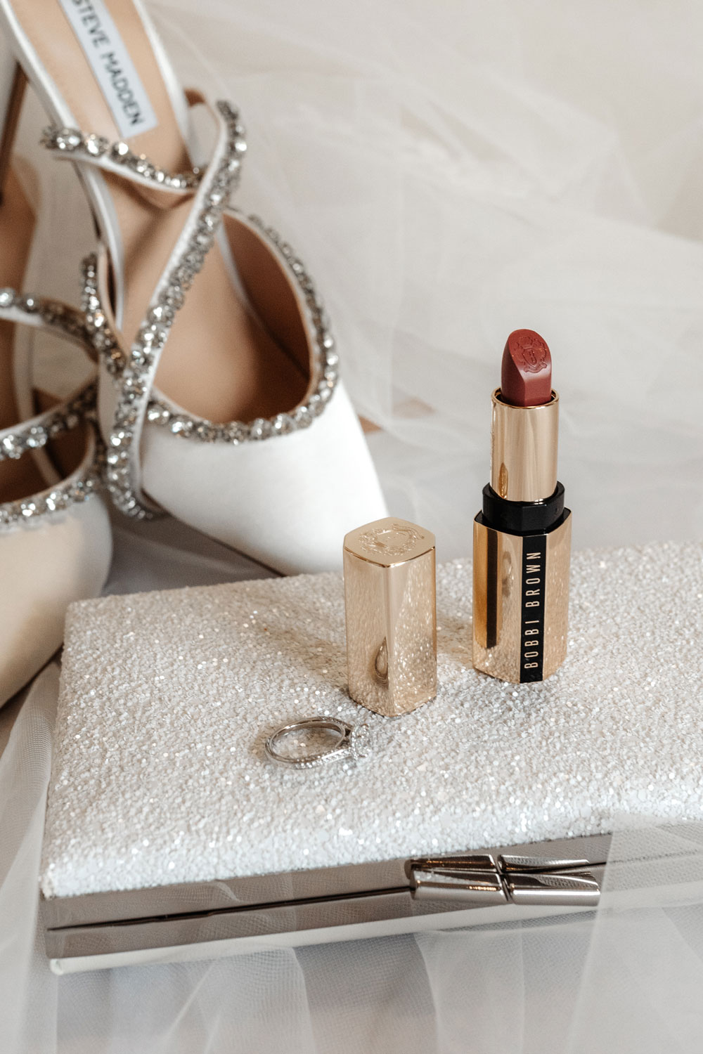 Bride's getting ready flat lay shot - shoes, bag, veil, lipstick and ring.